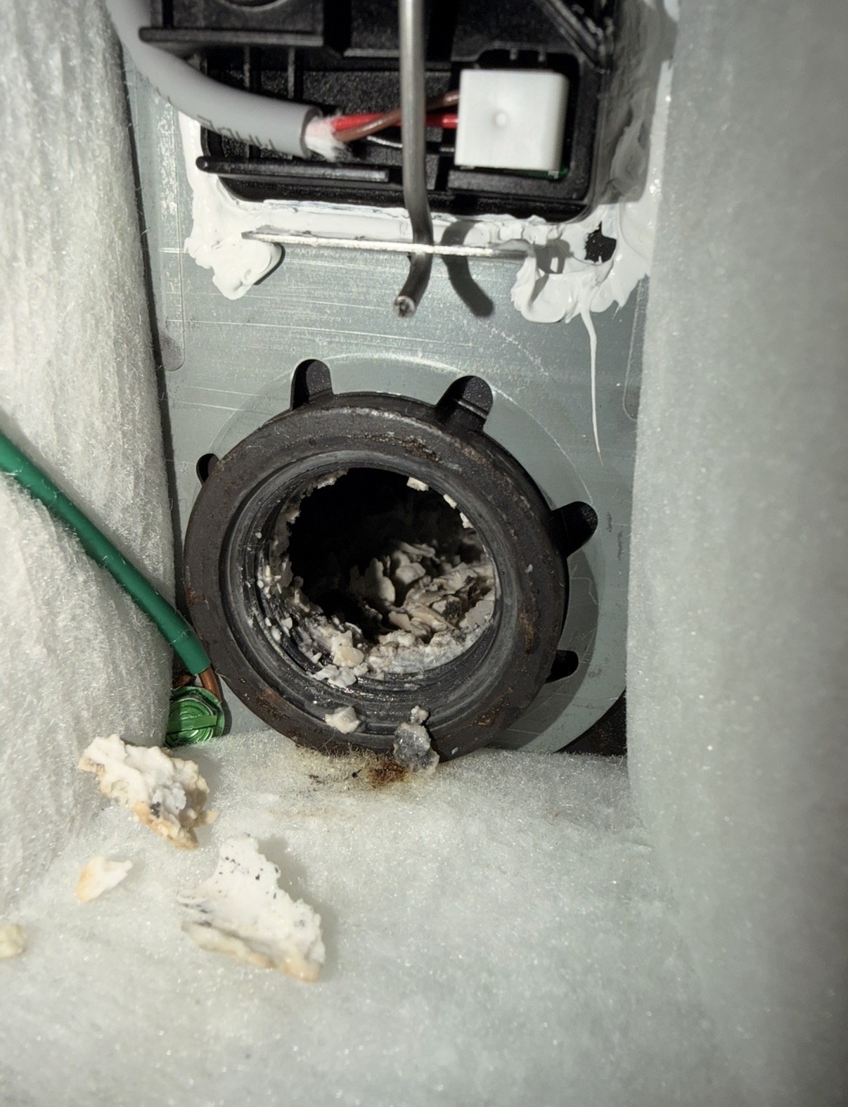 View through an open water heater element port showing heavy white mineral buildup inside the tank