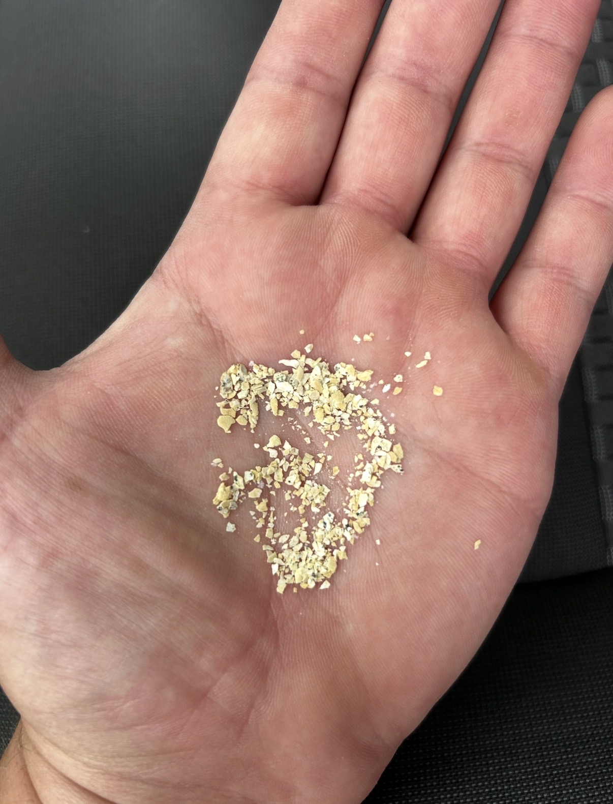 Mineral and sediment flakes held in an open hand
